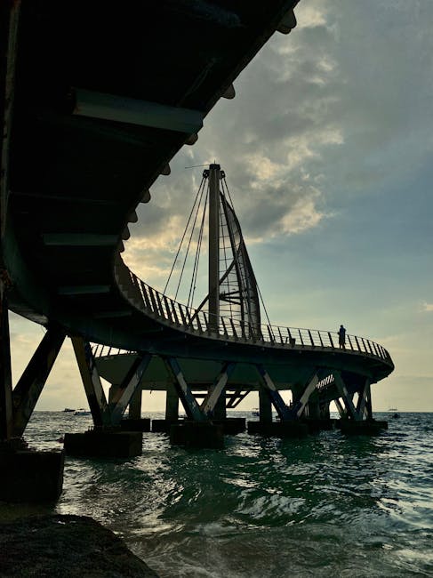 Silhouette of iconic Los Muertos Pier in Puerto Vallarta against a sunset sky.